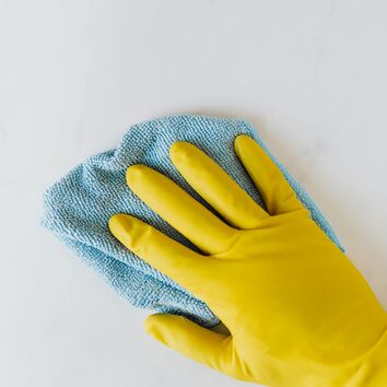 Hand in Gummihandschuh beim reinigen einer Fläche